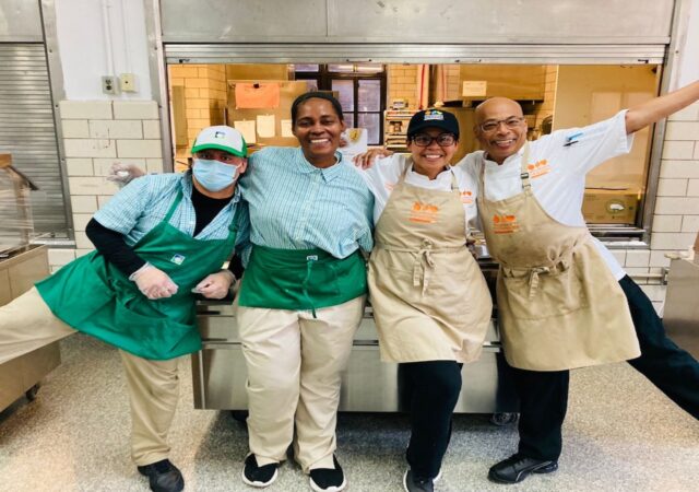 Four chefs smiling with their arms around one another.